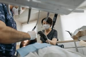 Deux dentistes effectuant une intervention dentaire sur un patient dans un environnement clinique moderne.