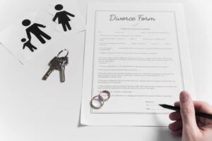Formulaire de divorce officiel, clés de maison et alliances posés sur une table blanche pour illustrer une procédure de divorce à Chambéry
