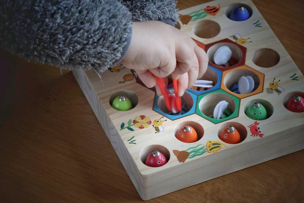 Une main utilise des pinces rouges pour placer des boules colorées