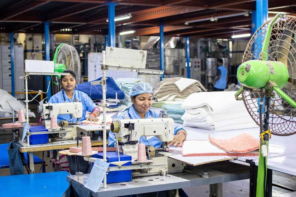Femmes en blousons bleus coudant dans une usine de textile