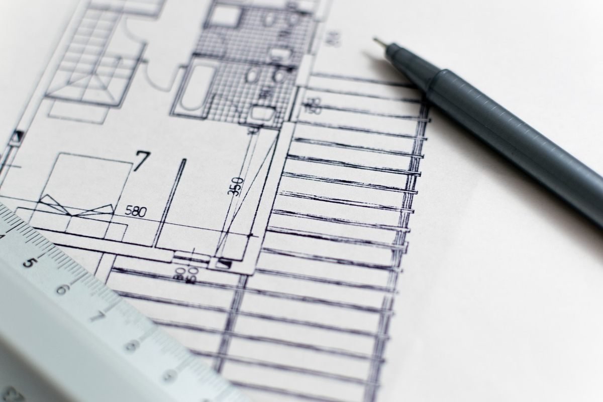 Feuille de plan, stylo et règle posés sur papier blanc