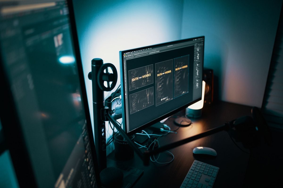 Un poste de travail avec écran clavier souris et micro dans une pièce sombre